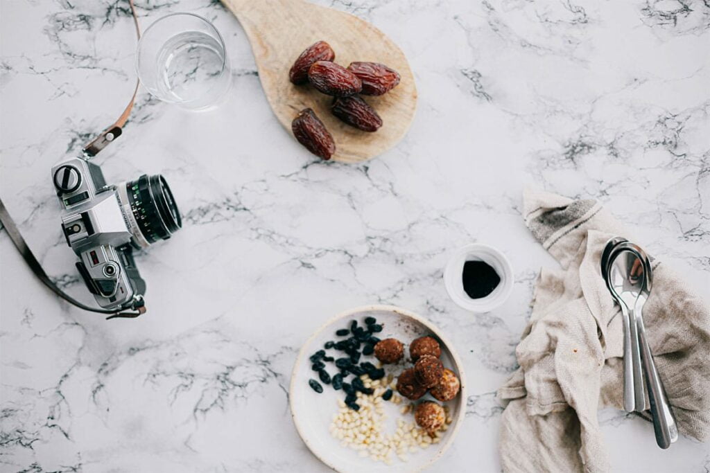 A plate of food on a marble table with a camera and utensils.