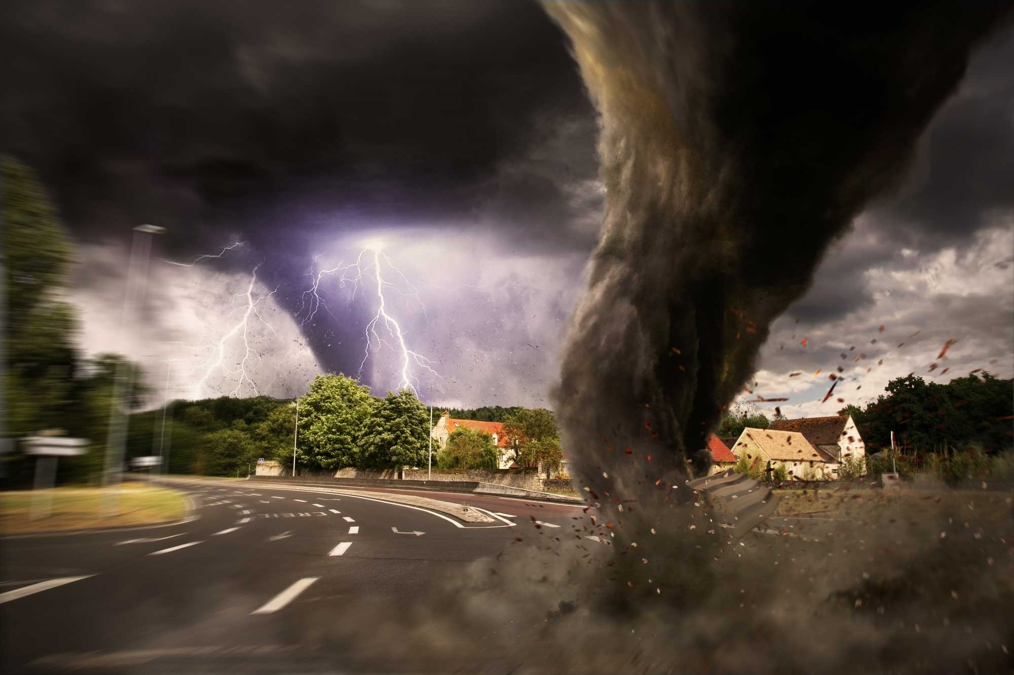 An image of a tornado in the sky with a city in the background.