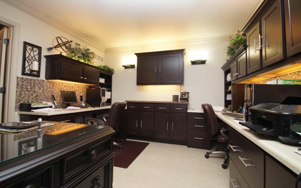 A home office with black cabinets and a desk.