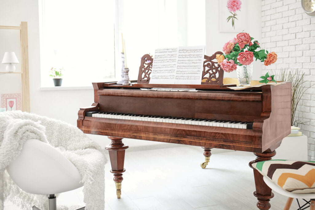 A piano in a room with white walls and a white chair.