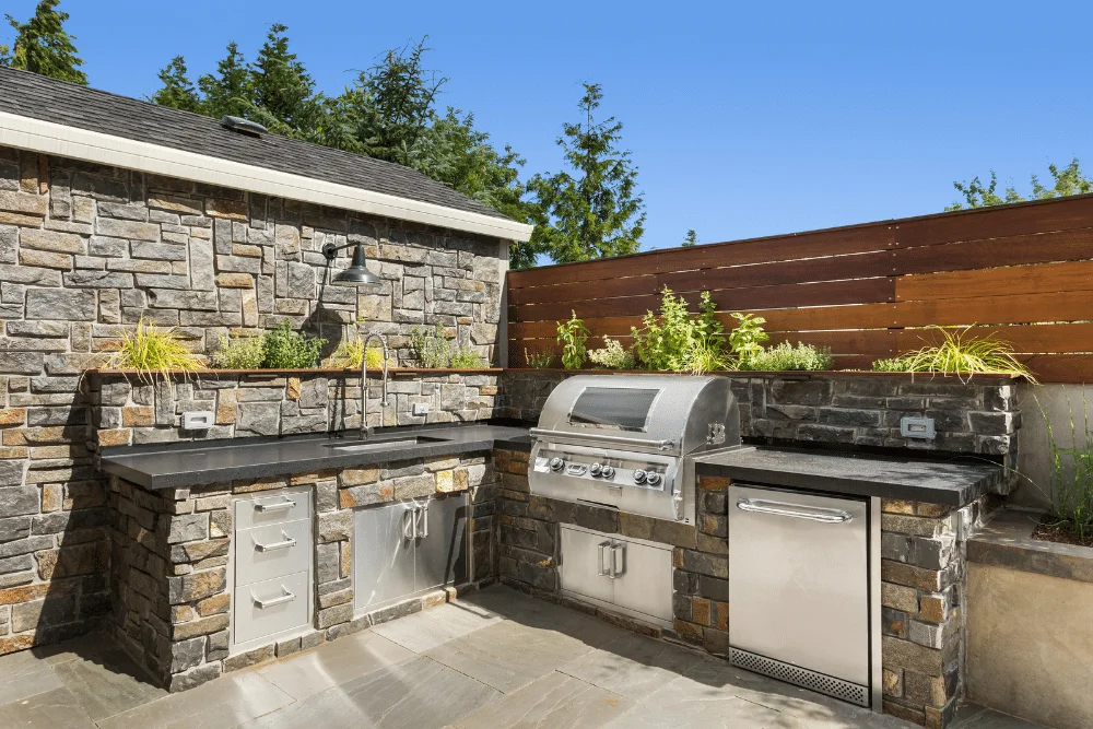 An outdoor kitchen with a grill and sink.