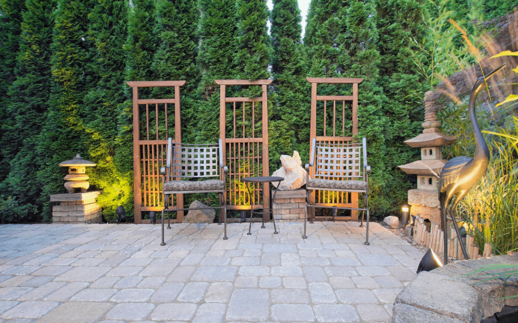 A stone patio with a wooden table and chairs.