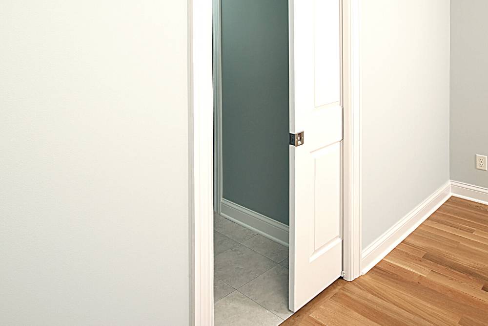 A room with a white door and hardwood floors.