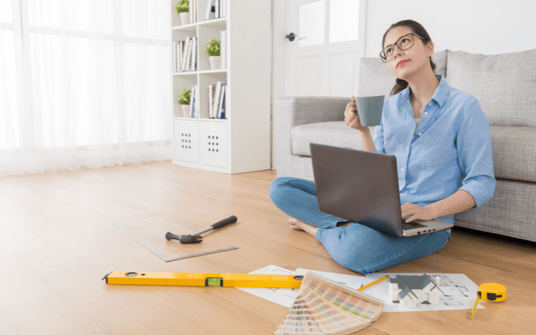 A woman sitting on the floor with a laptop and tools.