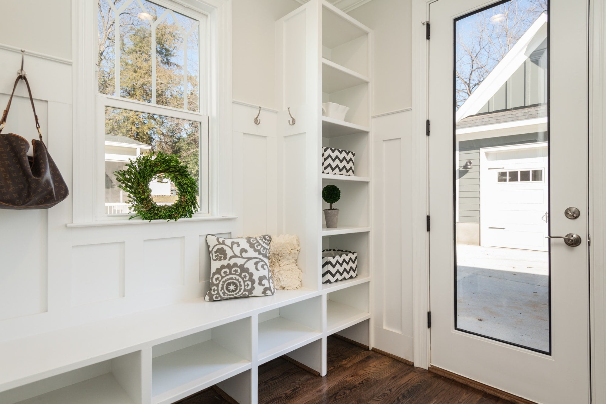 A white entryway with a bench and bookshelves.