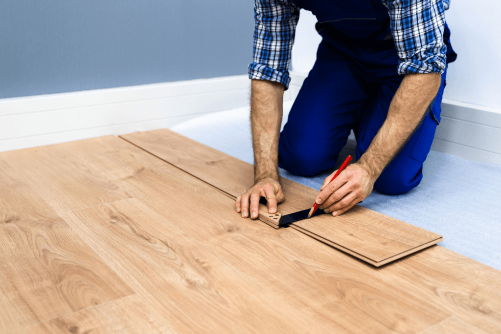 A man is installing a wooden floor in a room.