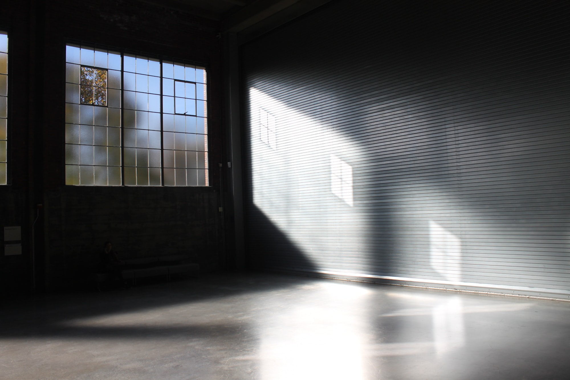 A room, transformed from garages, with a large window and a concrete floor.