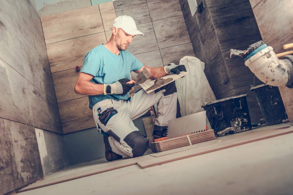 A man working on a tile floor in a bathroom.