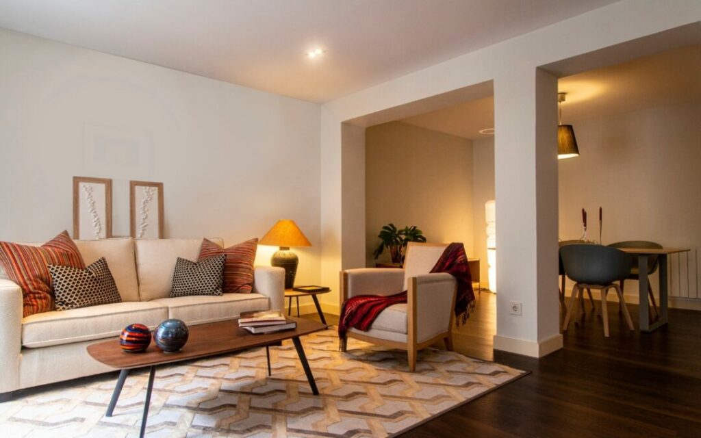 A small living room with wooden floors and a white couch, featuring creative lighting ideas.