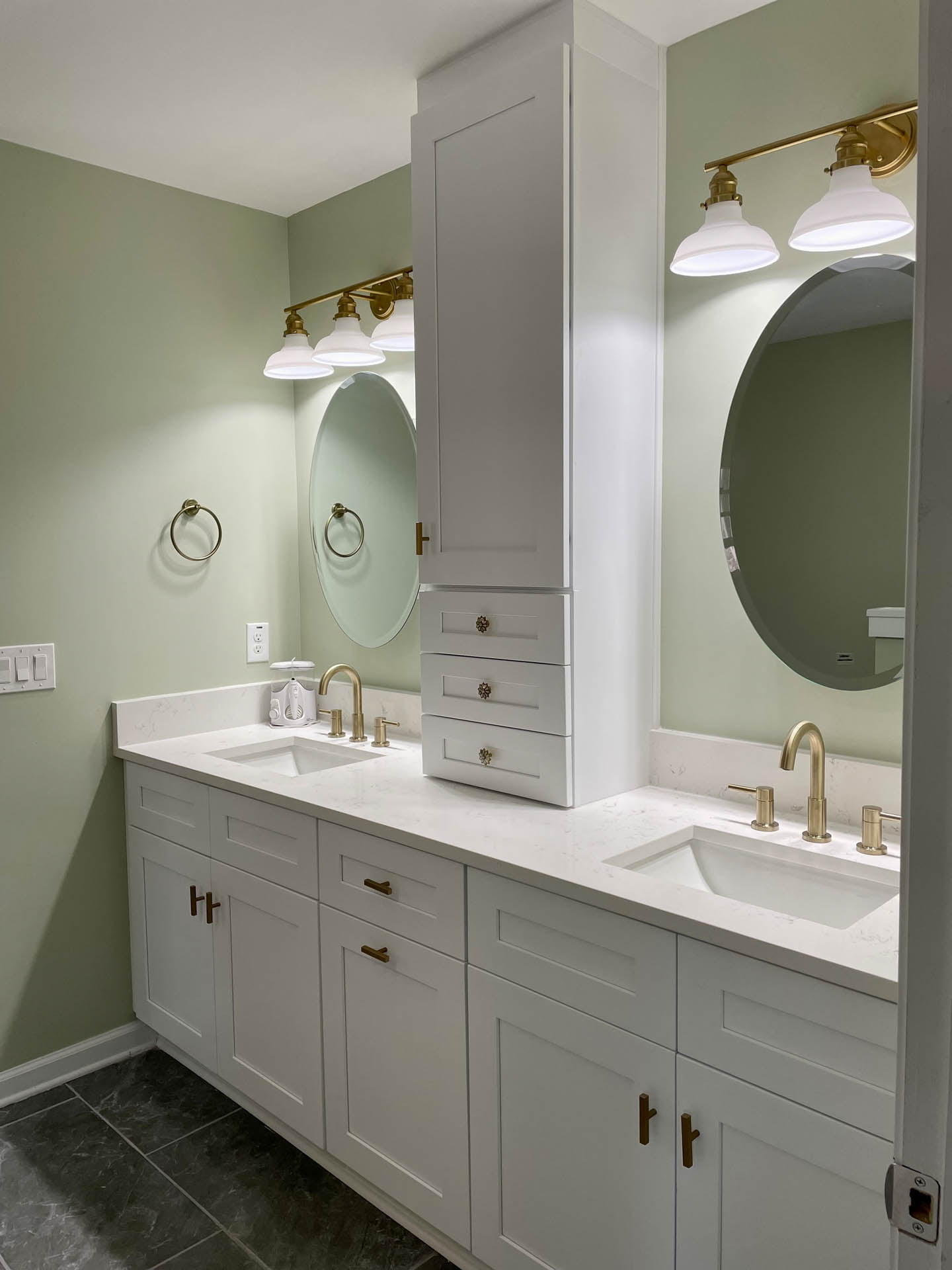 A bathroom with two sinks and a round mirror.