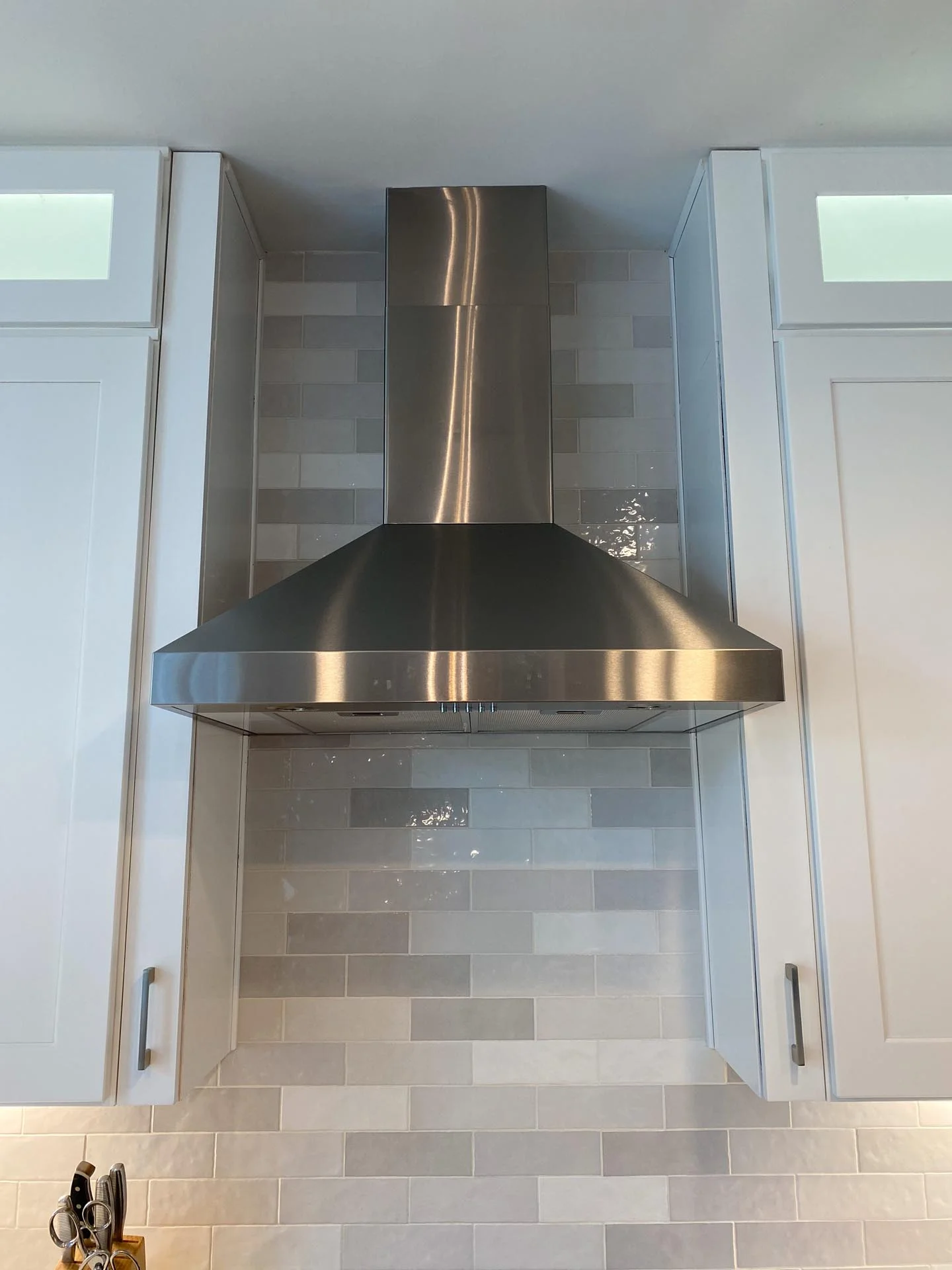 A kitchen with a stainless steel range hood.