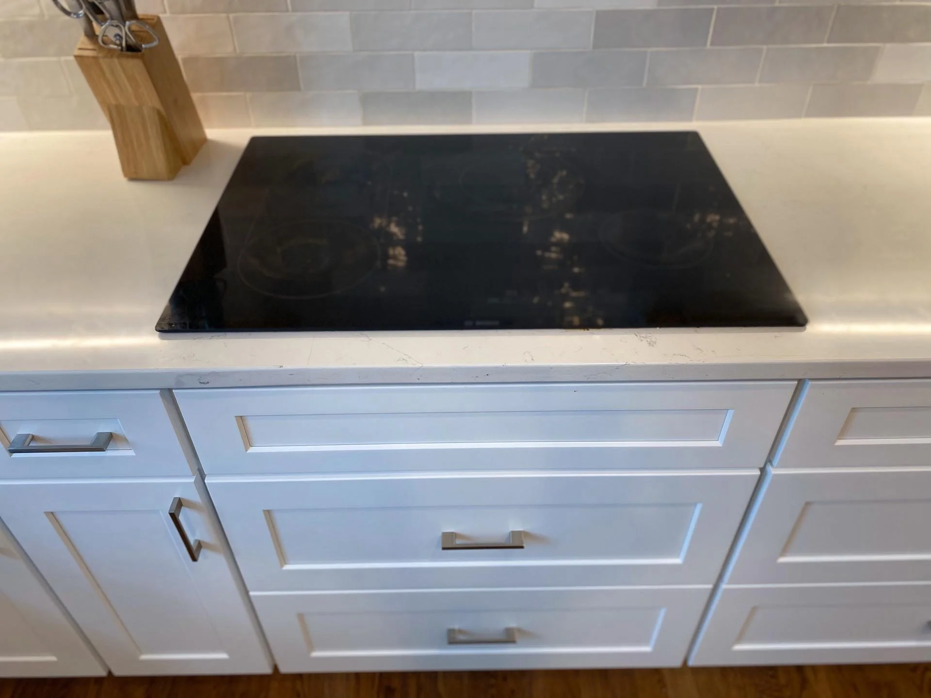 A white kitchen with a black stove top.