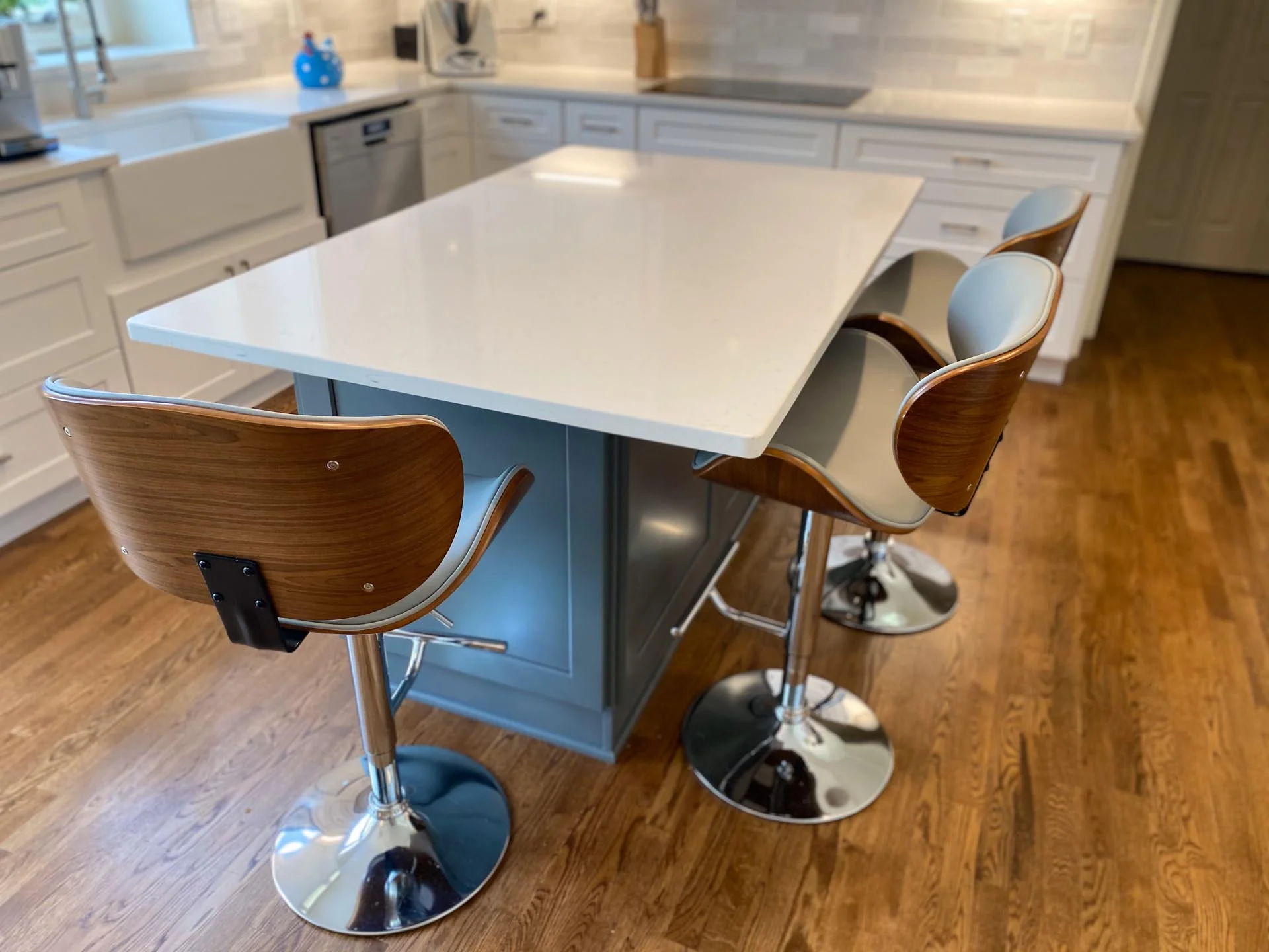 A kitchen island with two stools and a white countertop.