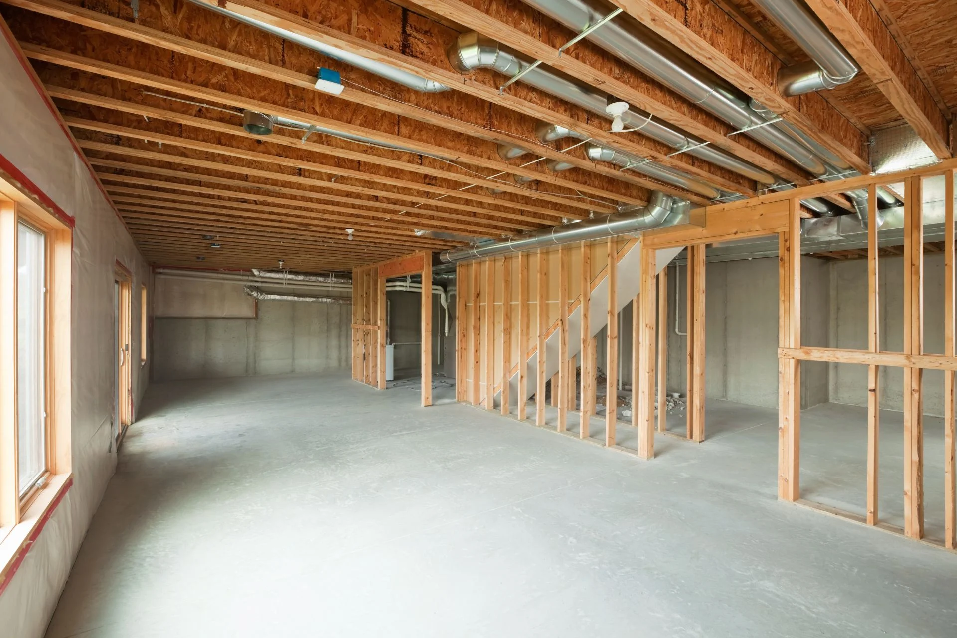 An unfinished basement with wood framing and wood beams.