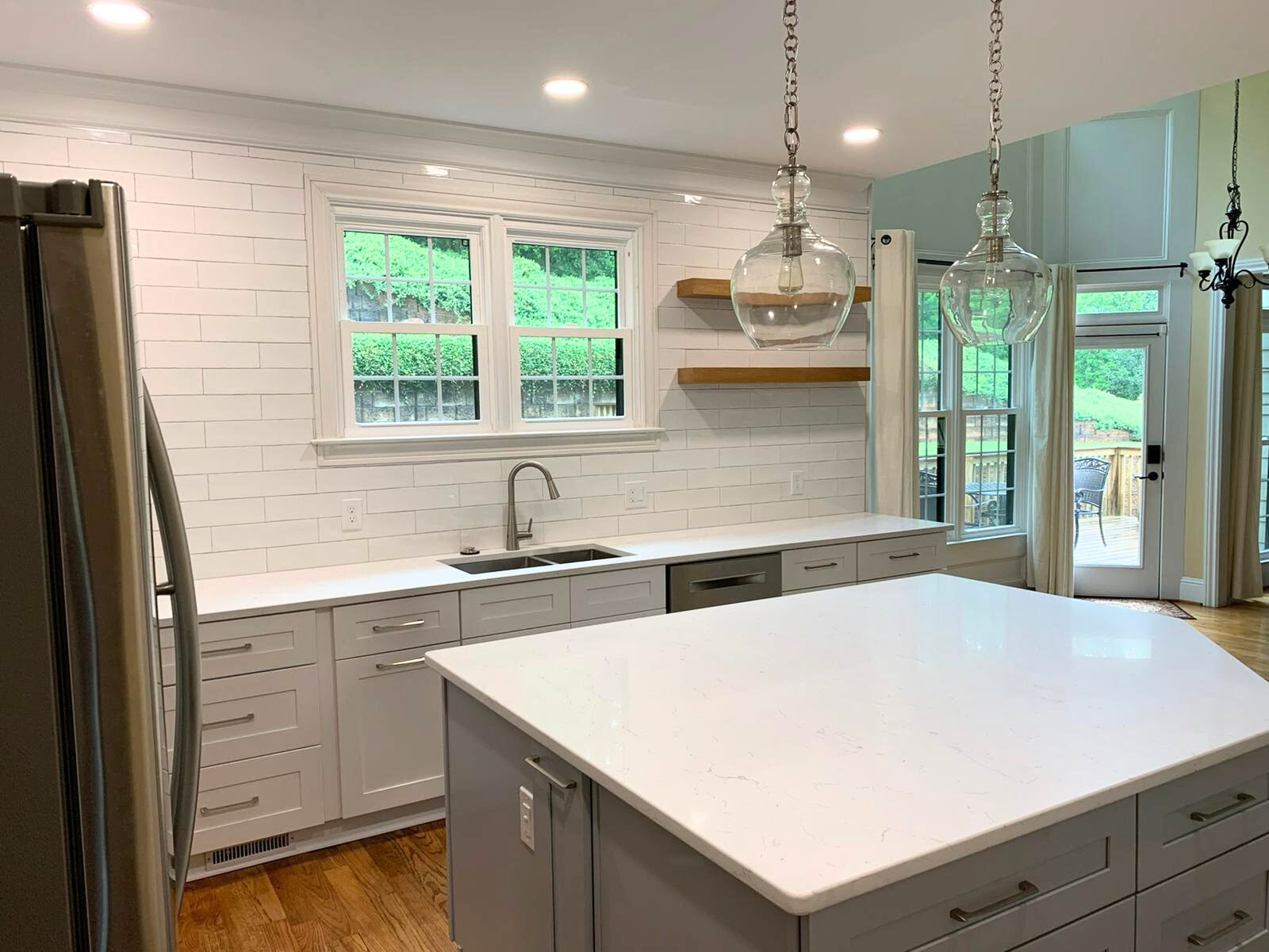 A kitchen with a white island and stainless steel appliances in a Footer design.