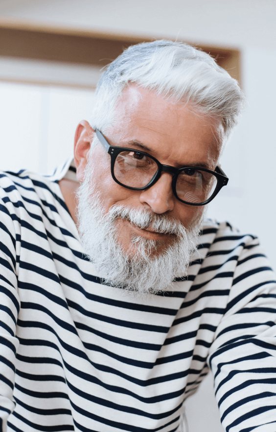 An older man wearing glasses and a striped shirt.