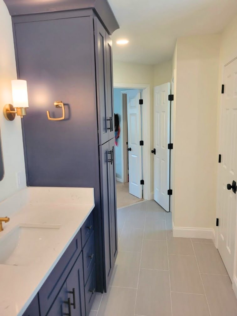 About Us: A bathroom with blue cabinets and white counter tops offers a stylish and contemporary design. The contrasting colors of the cabinets and counter tops create a visually appealing look, making this bathroom a standout feature