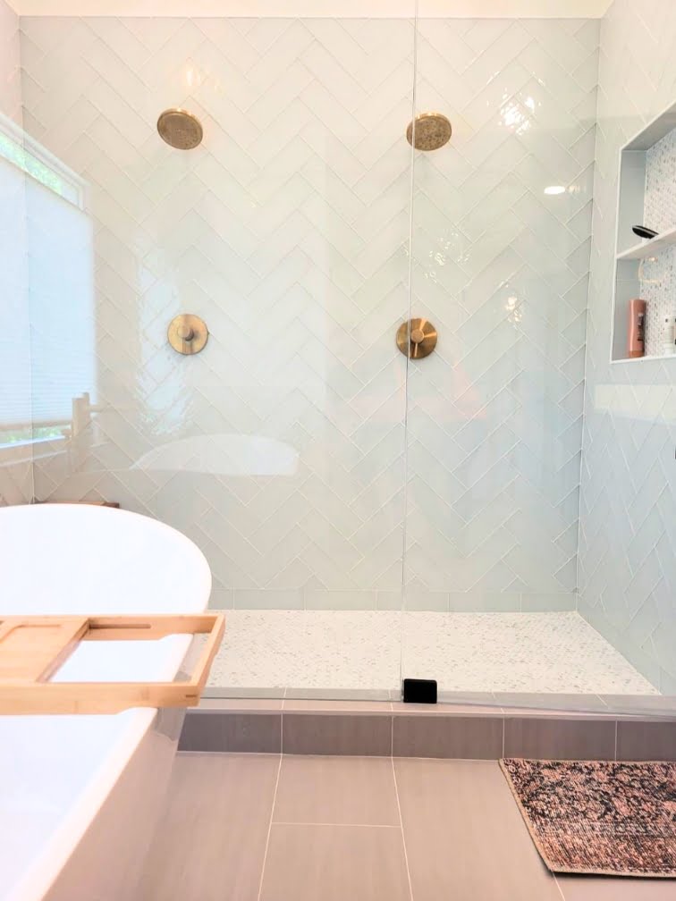 A home bathroom with a glass shower door and a bathtub.