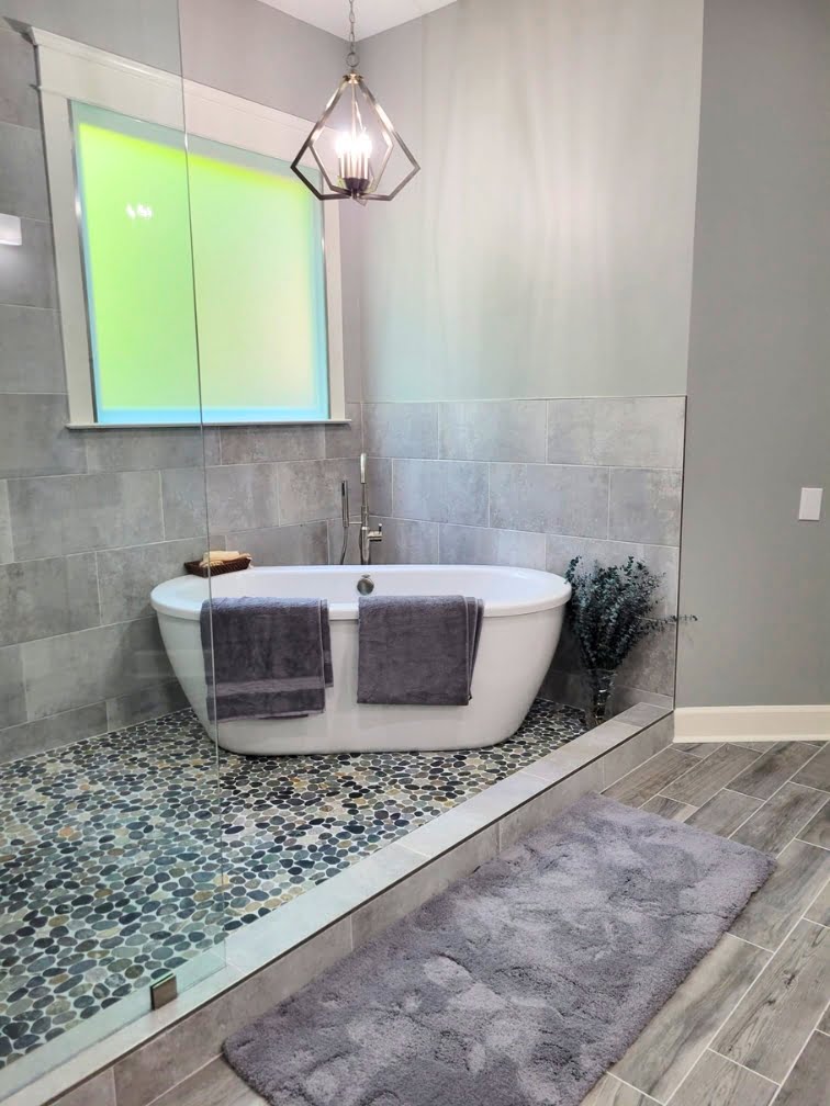 A home bathroom project by FD Remodeling with a gray tile floor and a bathtub.