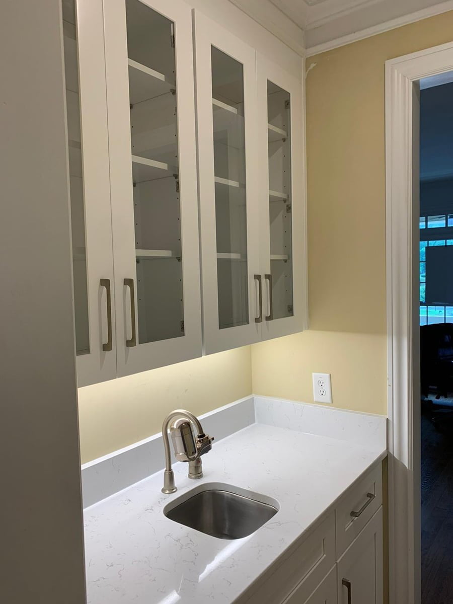 A white cabinet kitchen in a cozy home, complete with a sink.