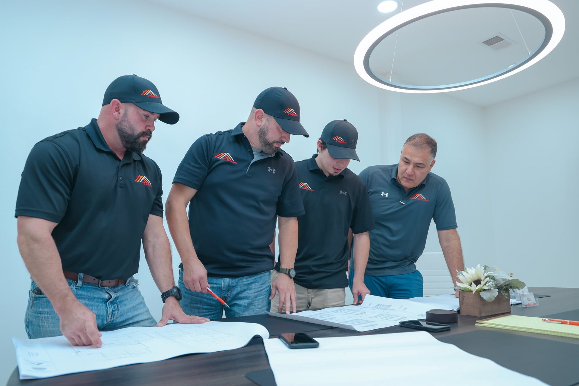 Four men standing around a table looking at blueprints for a home.