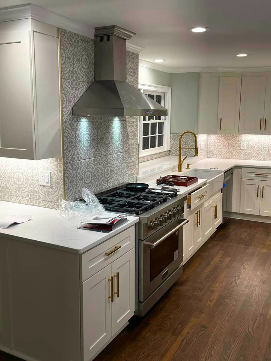 Residential home remodeling services for a white kitchen with stainless steel appliances and wood floors.