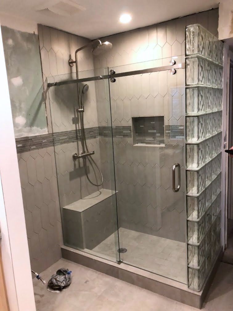 A bathroom remodeling project includes the installation of a glass shower door.