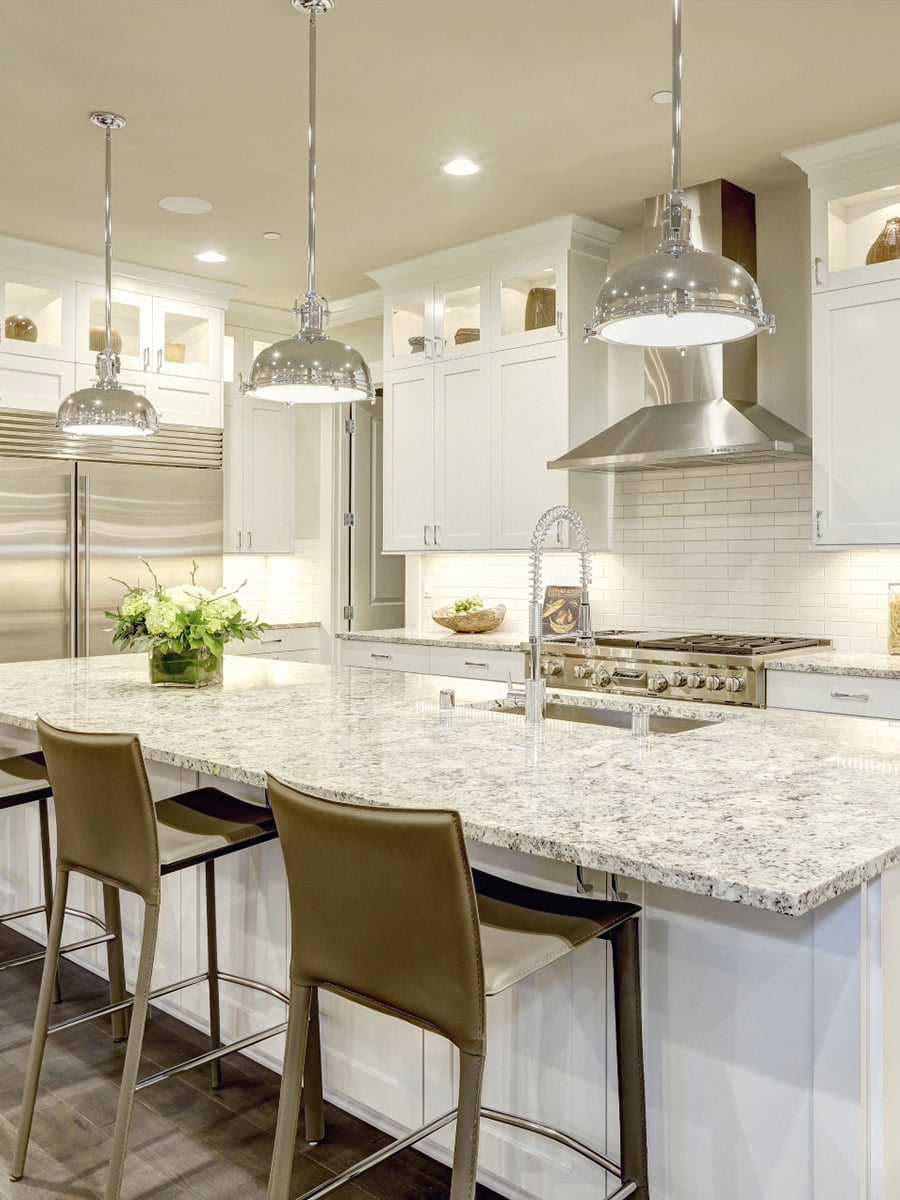 A white kitchen with granite counter tops and stainless steel appliances in a cozy home.