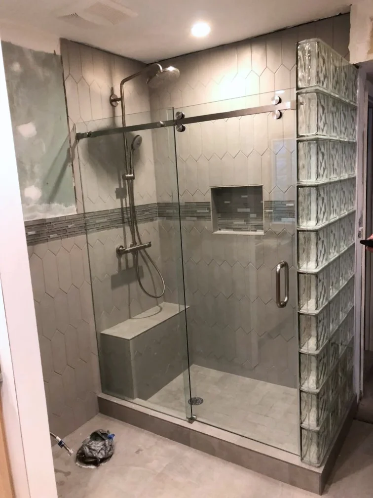 A glass shower door is being installed in a bathroom.