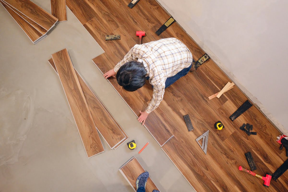 A man is installing wood flooring in a room, following the latest home remodeling trend.