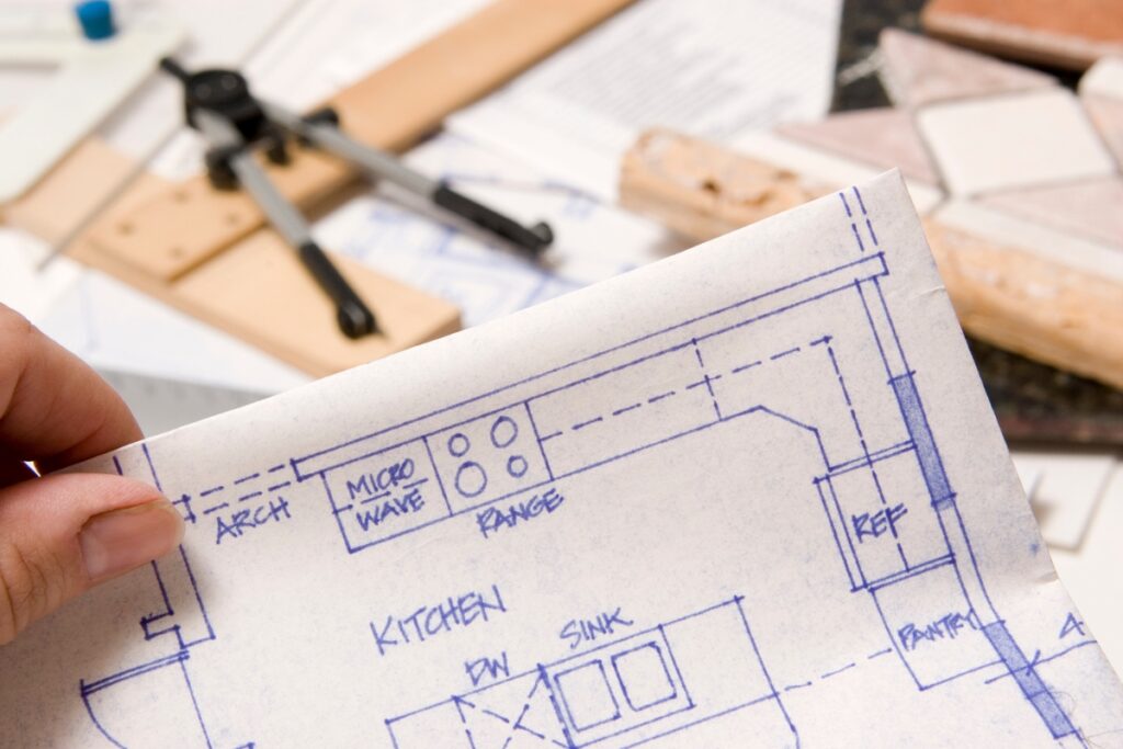A person holding a blueprint of a kitchen to plan the remodeling budget.