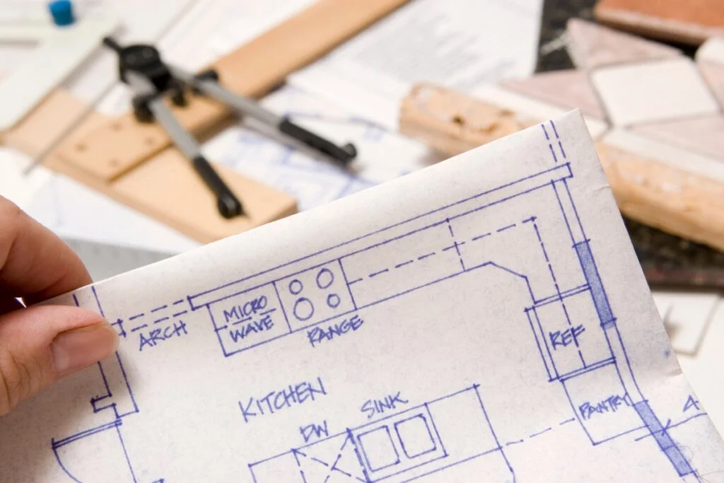 Remodeling Budget Breakdown: How to Make Every Dollar Count 5 A person holding a blueprint of a kitchen to plan the remodeling budget.