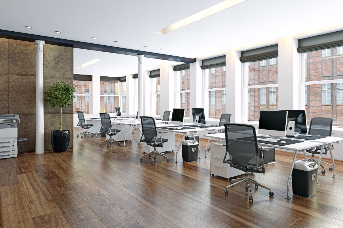 A modern office layout with many desks and a large window.