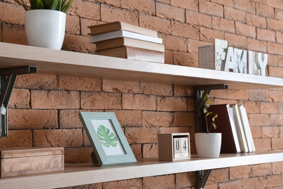 A decorative wall shelf with books and a plant on it.