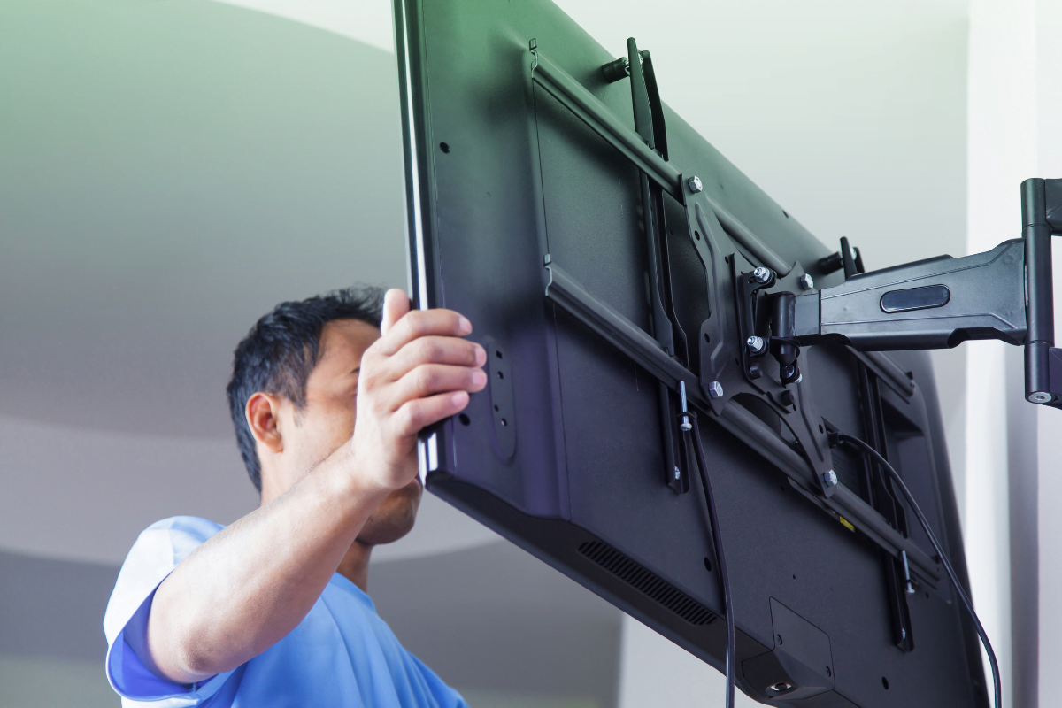 A man holding a tv, trying to hide the wires.