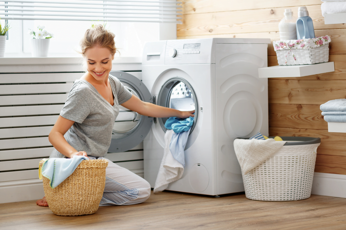 A woman putting clothes into a washing machine in one of the laundry room layouts.