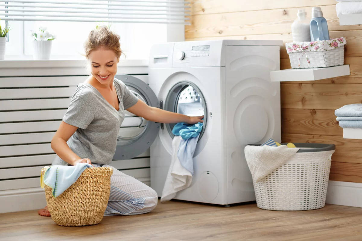 Maximizing Space With Creative Laundry Room Layouts 3 A woman putting clothes into a washing machine in one of the laundry room layouts.