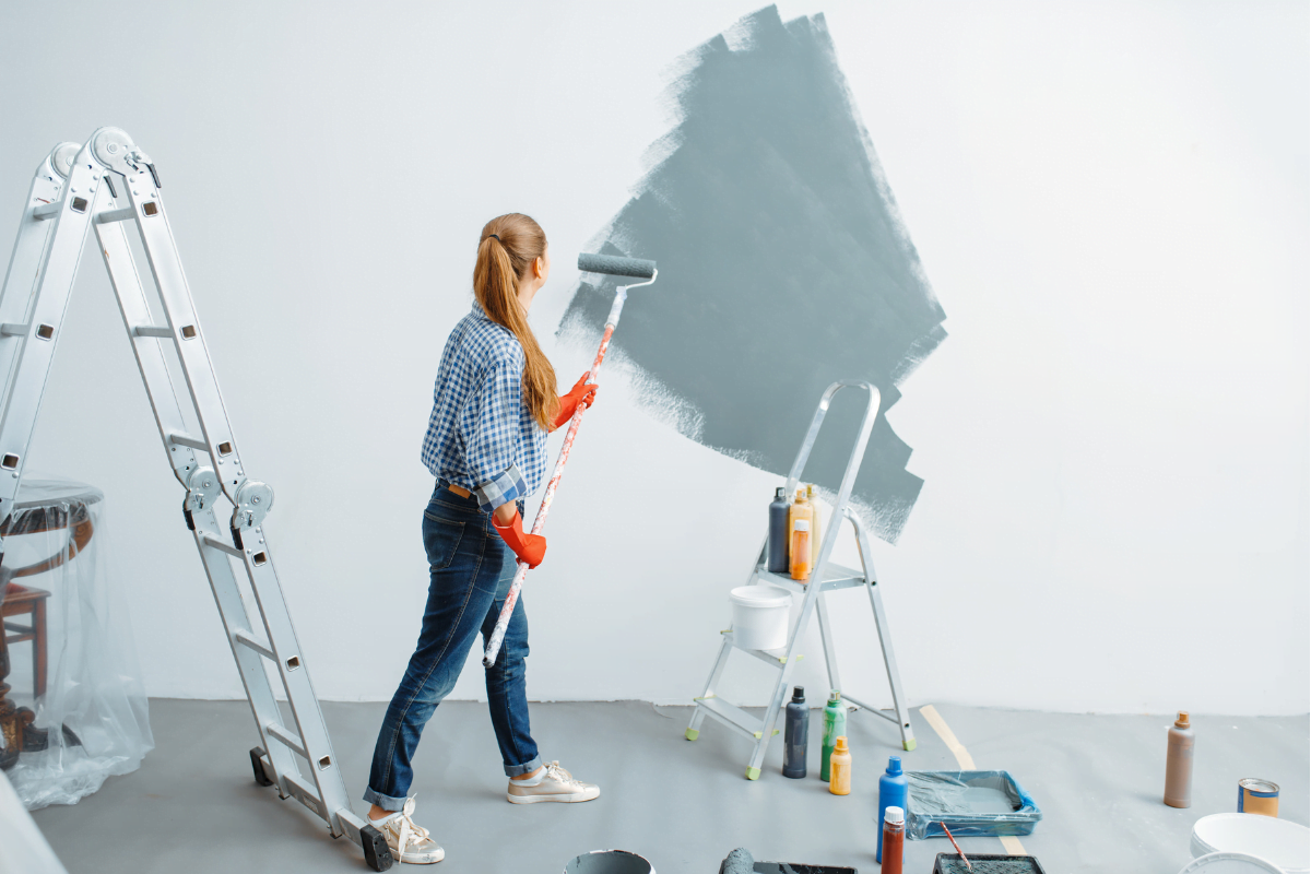 A woman painting a wall with a paint roller.