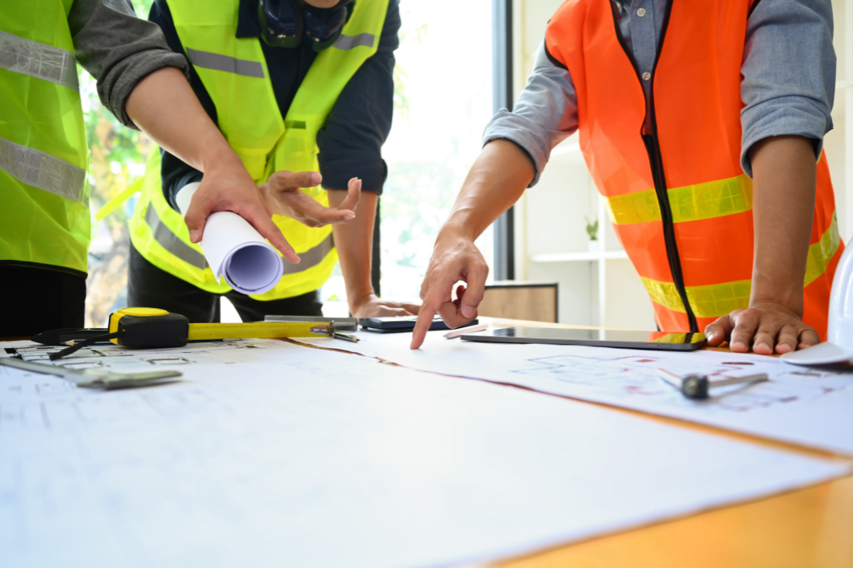 A group of construction workers looking at blueprints for project management in construction.