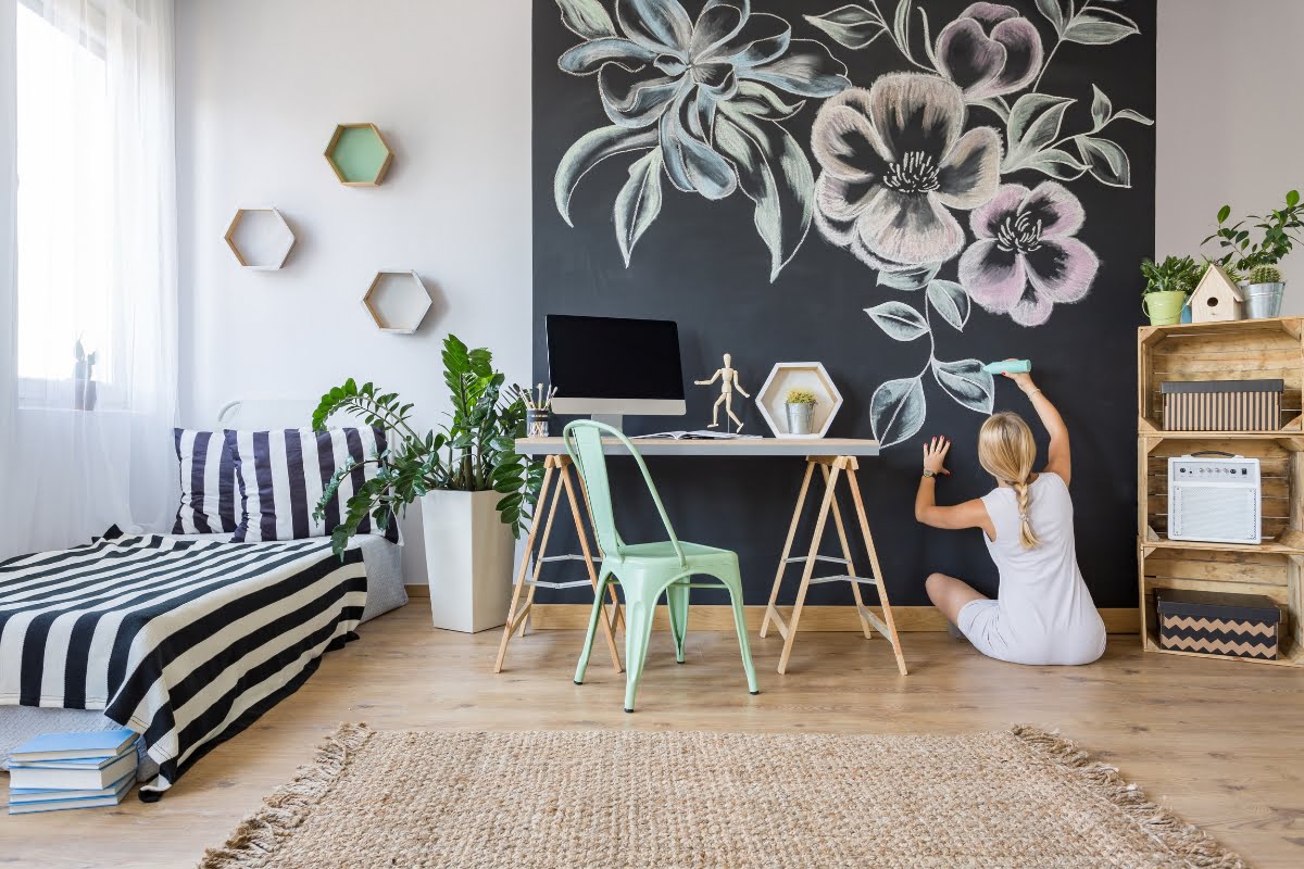 A woman painting flowers on a bedroom focal wall.