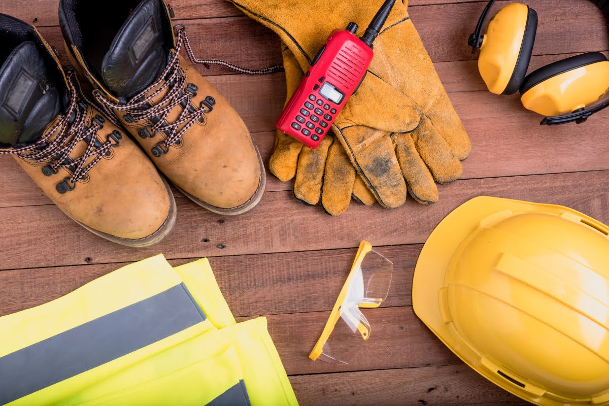 Personal protective equipment adhering to safety standards in construction and a walkie-talkie on a wooden surface.