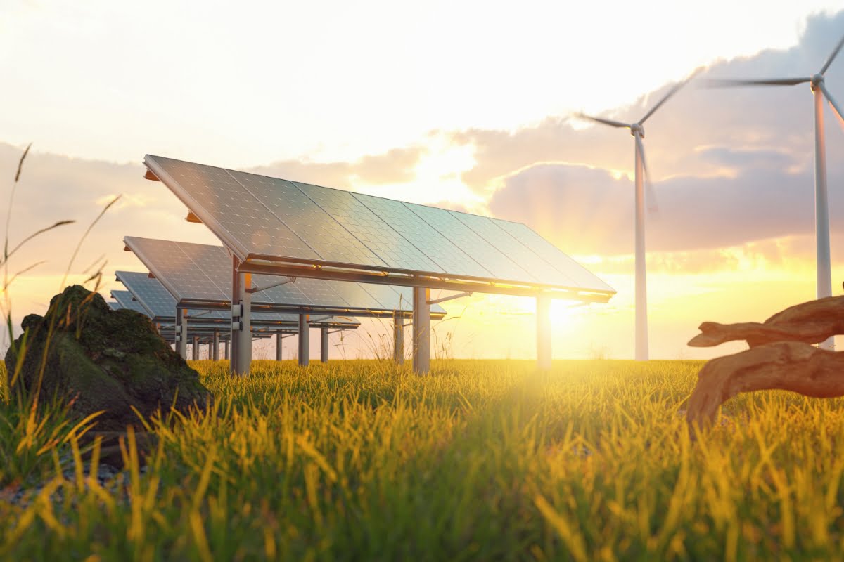 Solar panels and wind turbines in a grassy field at sunset symbolize renewable energy sources, highlighting the importance of energy efficiency in homes.