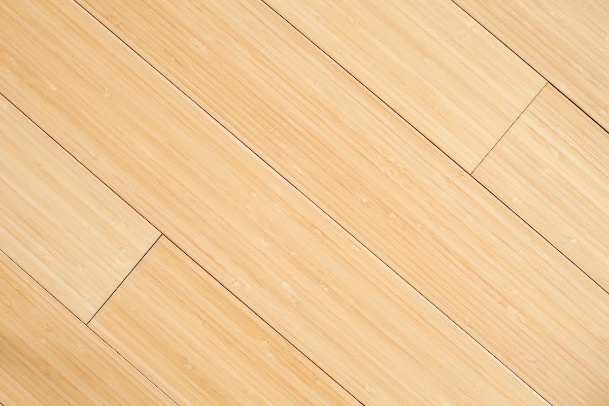 A close-up of a light-colored, smooth wooden floor with parallel planks aligned diagonally, crafted from sustainable building materials.