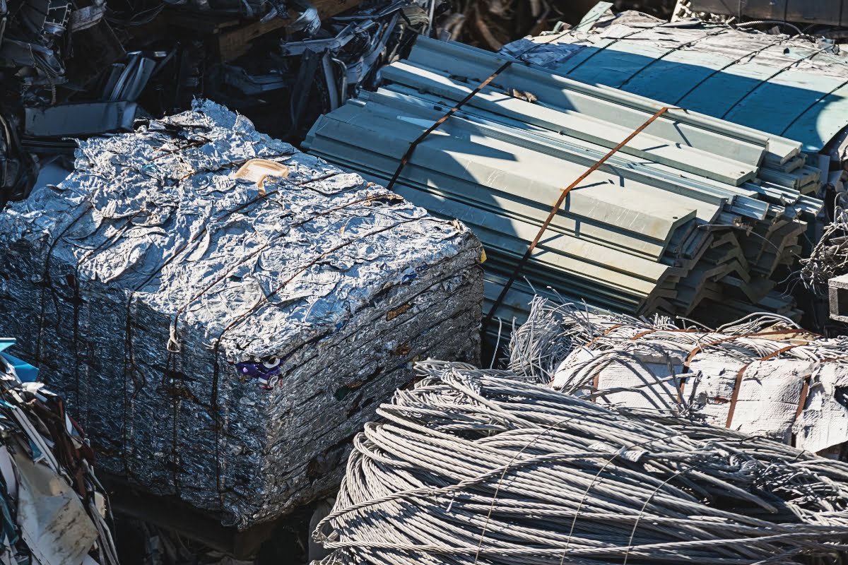 Aerial view of compacted metal bales, aluminum sheets, and coiled wires at a recycling yard, showcasing the potential for sustainable building materials.