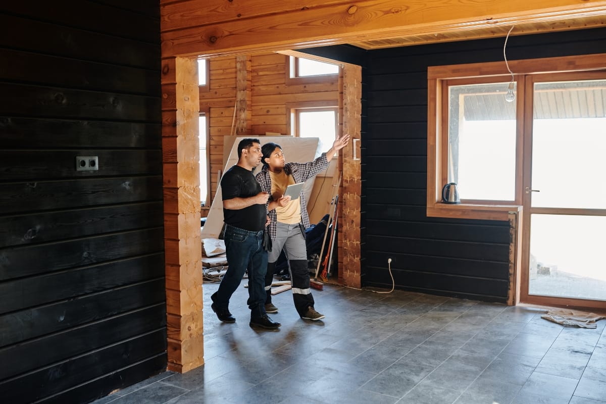 Step-by-Step Remodeling Process: How to Renovate Your Roswell Home Seamlessly 9 Two people stand in a partially renovated wooden room, one pointing towards the window while discussing details of the remodeling process.