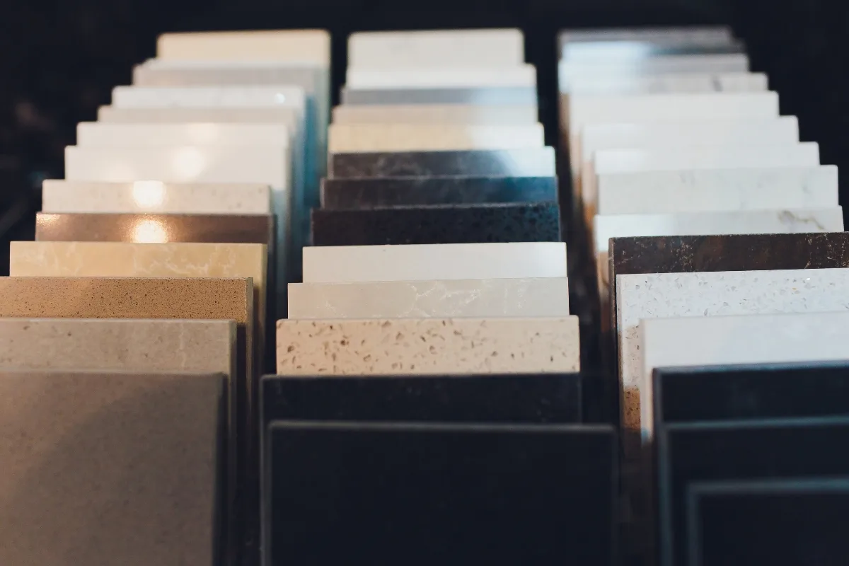 Rows of rectangular countertop material samples in various colors and finishes are displayed upright in a showroom, offering inspiration for kitchens and outdoor patios alike.