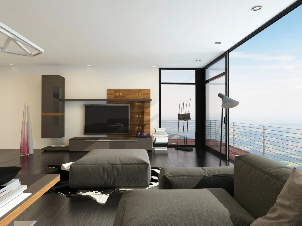 Modern living room with large windows, a grey couch, TV, floor lamp, and decorative items&mdash;perfect for condo remodeling&mdash;with a balcony offering a scenic landscape view.
