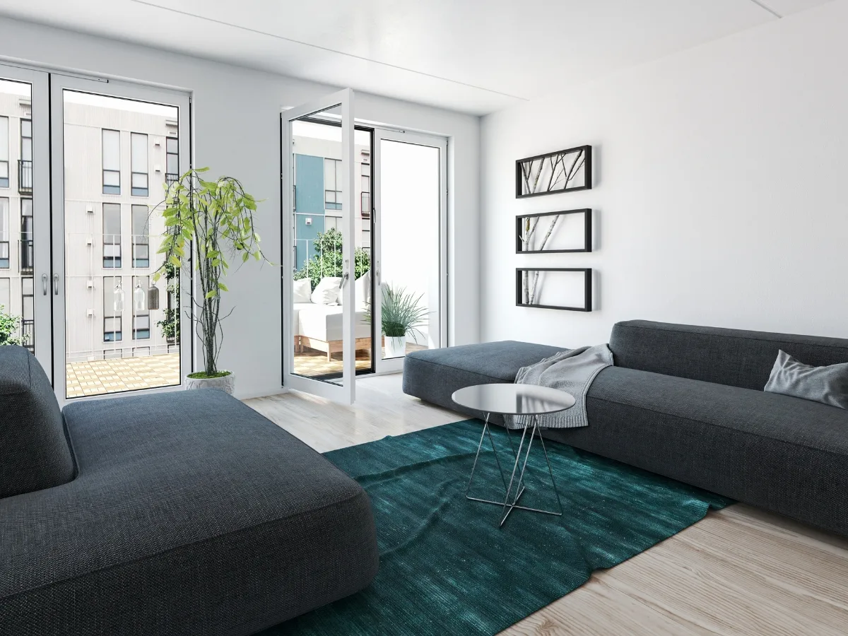 Modern living room showcases dark gray sofas, a round coffee table, green rug, wall art, a potted plant, and glass doors leading to a balcony with city views&mdash;perfect for stylish condo remodeling.