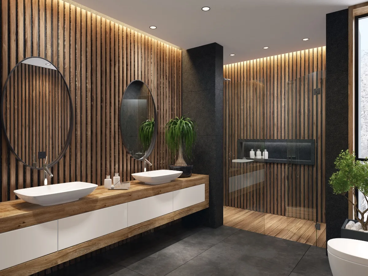 Experience Buckhead GA luxury bathroom remodeling in this modern space featuring wood slat walls, double sinks, round mirrors, a walk-in glass shower, and lush potted plants.