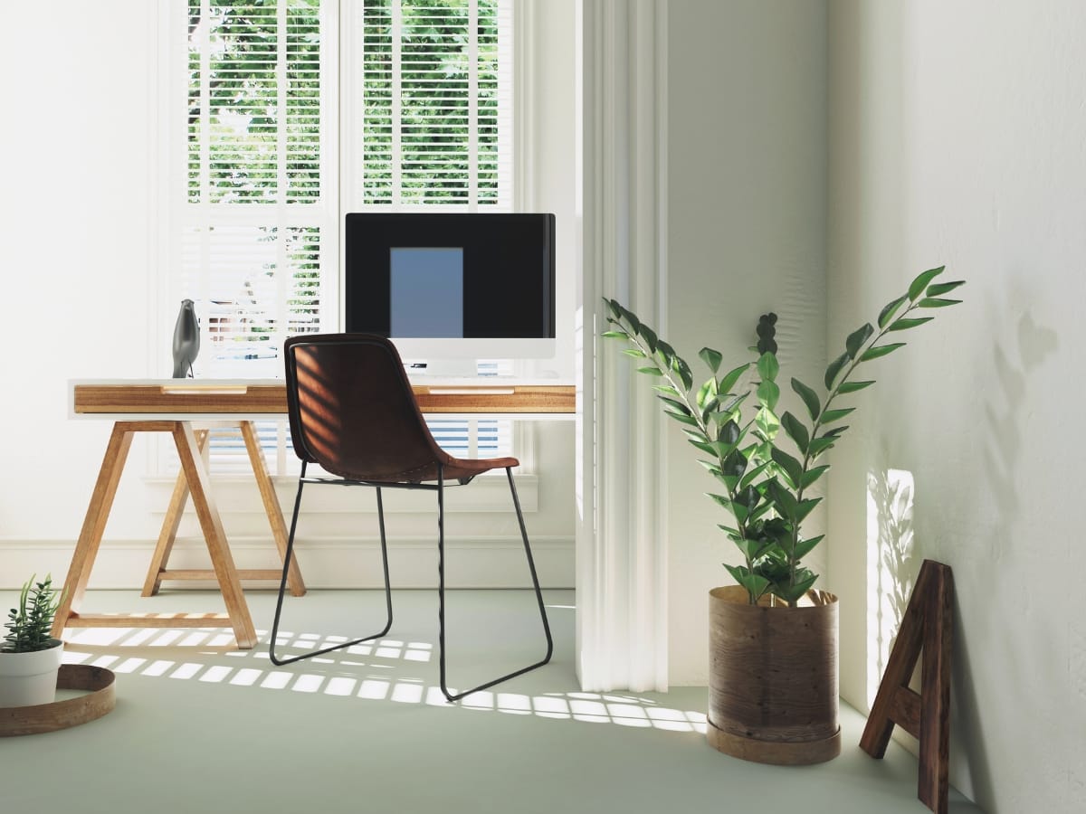 Brookhaven GA Home Office Remodeling Ideas for a Productive Workspace 5 A modern home office remodeling features a wooden desk, computer, black chair, potted plants, and a large window with blinds letting in sunlight.
